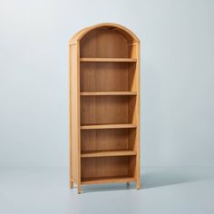 a wooden bookcase sitting on top of a white floor next to a blue wall