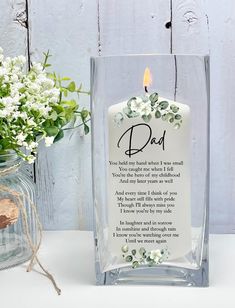 a candle that is sitting next to a vase with flowers in it and a message on the front