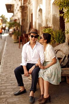 a man and woman sitting on a bench in the middle of an alleyway together