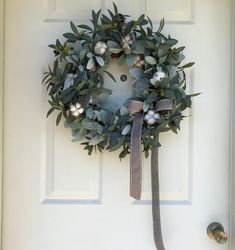 a wreath is hanging on the front door with a ribbon tied around it to hang