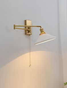 a wall light with a white shade hanging from it's side in a room