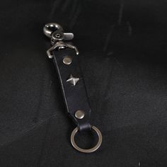 a black leather keychain with silver stars on it's side and a metal ring at the end