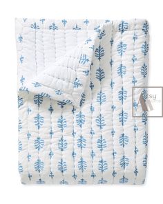 a blue and white quilted comforter with leaves on the front, in an image