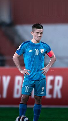 a soccer player standing on the field with his hands on his hips and looking down