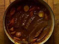 a pot filled with meat and potatoes on top of a wooden table