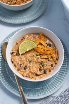 two bowls filled with soup and topped with tortilla chips next to a spoon