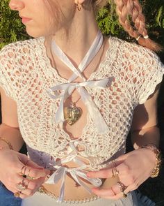 a woman with braids wearing a white top and holding her hands in her pockets