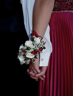 the bride and groom are holding hands in their wedding attire with red pleated skirts