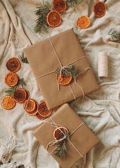 two wrapped presents sitting on top of a bed next to orange slices and cinnamons