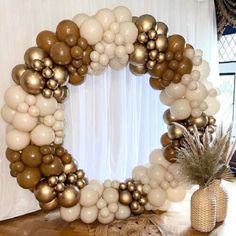 a white and gold balloon wreath on top of a wooden table