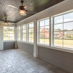 an empty room with two windows and a ceiling fan in the middle of it,