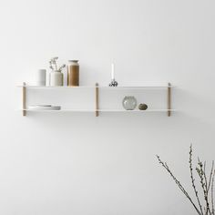 two white shelves on the wall with vases and other items sitting on top of them