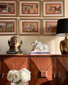 a table with vases and pictures on the wall above it, along with a lamp