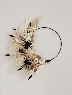 an arrangement of dried flowers and feathers on a headband, photographed against a white background