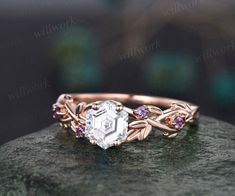 a close up view of an engagement ring on top of a rock with leaves and stones