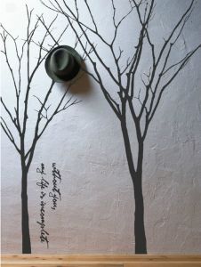 a hat is hanging on the wall next to two trees with words written in it