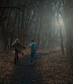 two people walking down a path in the woods