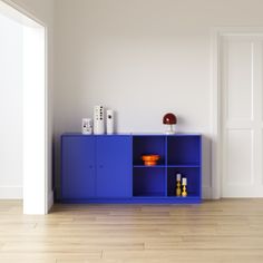 a blue cabinet sitting in the middle of a room next to a white wall and wooden floors