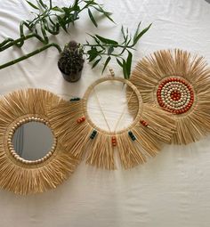 three pieces of art made out of straw sitting on top of a white tablecloth