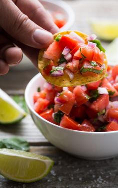 a person holding up a tortilla with tomatoes and onions in it to eat