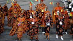 a group of people walking down a street with flags on their heads and in colorful outfits