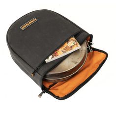 a black backpack with an orange lining and some food in the bottom compartment, on a white background