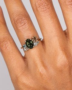 a woman's hand with a ring on it and a green stone in the middle