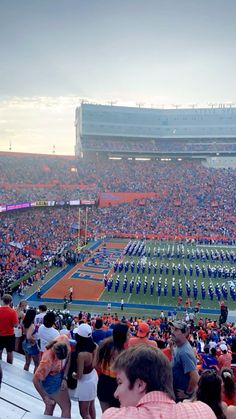 a stadium filled with lots of people standing on top of a field next to each other