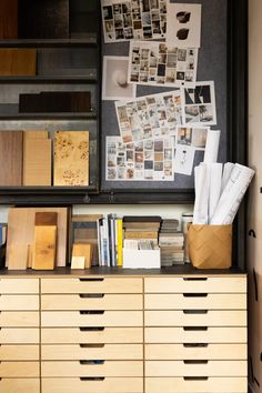 a cabinet with many drawers and pictures on the wall next to it is filled with papers