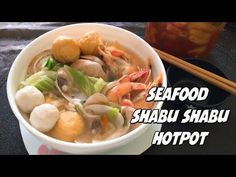 a bowl filled with seafood and vegetables next to chopsticks on top of a table