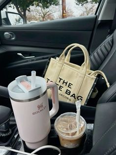 a starbucks cup, tote bag and other items in the back seat of a car