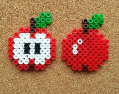 two apples made out of legos sitting on top of a corkboard floor next to each other