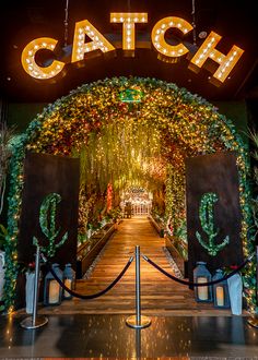 the entrance to catch is decorated with christmas lights and garlands, surrounded by greenery