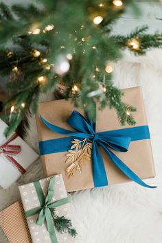 presents wrapped in brown paper under a christmas tree with blue ribbon and gold leaf decoration