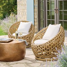 two wicker chairs sitting on top of a stone patio