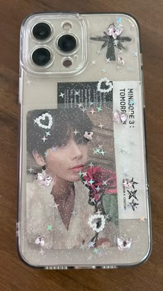 a phone case with an image of a woman and flowers on the back, sitting on a wooden surface