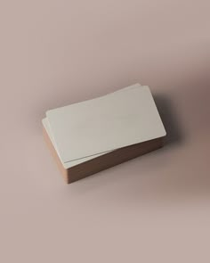 an empty white box sitting on top of a pink surface with a wooden base and lid