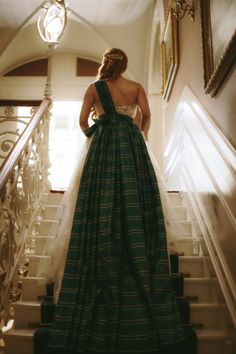 a woman in a green and white dress standing on stairs with her back to the camera