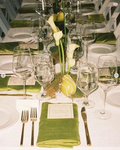 the table is set with white linens and green napkins, silverware, and flowers