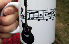 a person holding a coffee mug with musical notes on it and a guitar in the middle