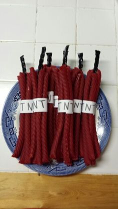 several pieces of red rope on a blue and white plate next to a tile wall