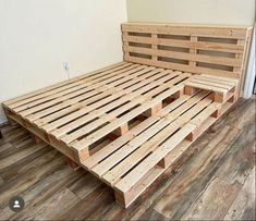 a bed made out of wooden pallets sitting on top of a hard wood floor