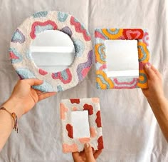 two hands holding up three different shaped mirrors and one has a mirror in the middle