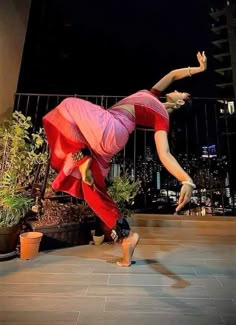 a woman is doing a handstand on the ground in front of some plants