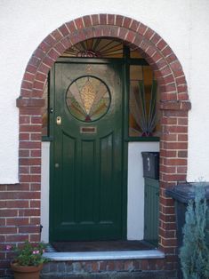 a green front door with stained glass on the top and bottom part, surrounded by brick arches