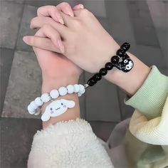 two people holding hands with bracelets on their wrist, one wearing a white and black beaded bracelet