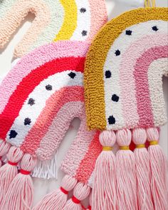 several knitted rainbows and tassels are on the table next to each other