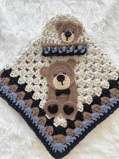 a crocheted teddy bear blanket on top of a white furry rug with two bears