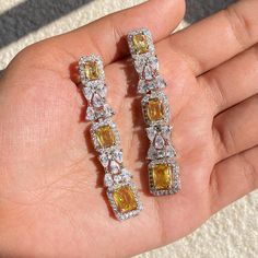 Yellow diamond earrings featuring fancy yellow diamonds and cubic zirconia in a statement design. Ideal Jewelry to pair with your bridal white gown and prom dress. Perfect gift for her or gift for sister. *𝐏𝐑𝐎𝐃𝐔𝐂𝐓 𝐃𝐄𝐓𝐀𝐈𝐋* * 𝐌𝐚𝐭𝐞𝐫𝐢𝐚𝐥: Brass * 𝐏𝐥𝐚𝐭𝐢𝐧𝐠: White Rhodium Plated * 𝐒𝐭𝐨𝐧𝐞: AAA-quality CZ Yellow Diamond *𝐃𝐈𝐌𝐄𝐍𝐒𝐈𝐎𝐍𝐒* * 𝐖𝐞𝐢𝐠𝐡𝐭: 7 gm each * 𝐋𝐞𝐧𝐠𝐭𝐡: 2.3 Inches * 𝐖𝐢𝐝𝐭𝐡:  0.4 Inches * 𝐂𝐥𝐨𝐬𝐮𝐫𝐞: Push Back 𝐕𝐢𝐬𝐢𝐭 𝐎𝐮𝐫 𝐅𝐀𝐐𝐬 Fine Jewelry Yellow Diamond Wedding Earrings, Luxury Yellow Diamond Earrings For Wedding, Formal Yellow Diamond Earrings With Diamond Cut, Luxury Yellow Diamond Drop Earrings, Diamond Earrings Wedding, Elegant Yellow Diamond-cut Earrings, Yellow Diamond Earring, Canary Diamond, Fancy Yellow Diamond