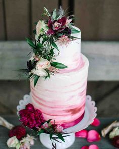 a wedding cake with pink and white frosting on the top is surrounded by flowers